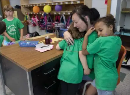  ?? MATHEW MCCARTHY, RECORD STAFF ?? Theresa Toschkoff, a Grade 1 teacher at St. Agatha Catholic School, is hugged by students on Friday. Toschkoff has taught at St. Agatha for 23 years, but now the school has closed for good.