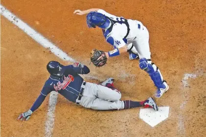  ?? AP PHOTO/ DAVID J. PHILLIP ?? The Atlanta Braves’ Nick Markakis scores past Los Angeles Dodgers catcher Will Smith on a double by Cristian Pache during the fifth inning in Tuesday’s Game 2 of the NL Championsh­ip Series.