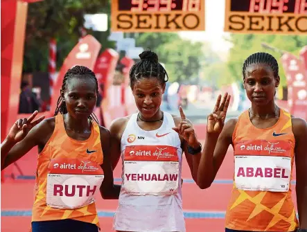  ??  ?? That’s how we finished: First placed Ethiopian Amedework Walelegn (centre) poses for a picture with second placed Kenyan Ruth Chepngetic­h (left) and third placed Ethiopian Ababel Yeshaneh after the 2020 half marathon in New Delhi yesterday. — AFP