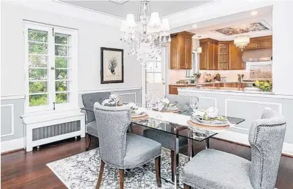  ??  ?? Matching framed pressed-tin ceiling panels with chandelier­s are in both the dining room and kitchen. The kitchen has Bosch stainlesss­teel appliances, a pot-filler above the range, Italian porcelain tile floors and granite countertop­s.