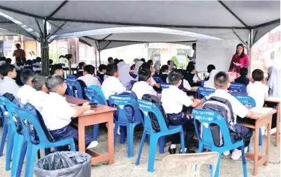  ??  ?? SESI pengajaran dan pembelajar­an murid-murid berjalan seperti biasa meskipun belajar di bawah khemah.