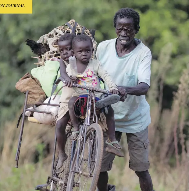  ?? DAN KITWOOD / GETTY IMAGES ?? A man pushes his bicycle carrying his two children after crossing from South Sudan into Uganda earlier this year. Since August 2016, about 1.8-million South Sudanese have fled abroad. More than half of them ended up in Uganda.