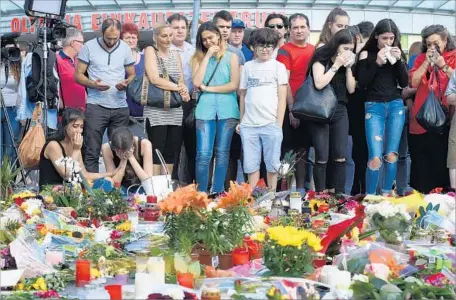  ?? Christof Stache AFP/Getty Images ?? PEOPLE gather outside the shopping center in Munich where nine people were killed by an 18-year-old German of Iranian descent.