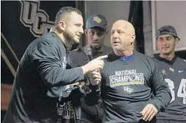  ??  ?? From left, Brandon Kravitz and Mike Bianchi of FM 96.9 revel in the chance to present UCF with the national championsh­ip trophy commission­ed by the “Open Mike” radio show.