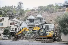  ?? ALEX BURTON THE ASSOCIATED PRESS ?? An excavator works on a home damaged by flooding and landslides in Auckland, New Zealand, on Sunday.