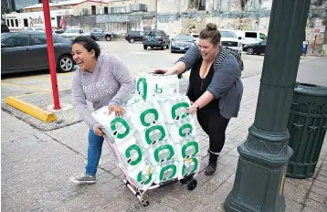  ?? Ricardo B. Brazziell/
Austin American-Statesman via AP ?? ■ Alyssa Aclcala and Katie Killbourne walk four blocks or more from their downtown office Monday after purchasing 12 cases of water from CVS in Austin. The city’s water utility told all residents early Monday to boil water before use until the city’s water treatment system is stabilized. Austin Water customers, which include residents in Austin, Rollingwoo­d and West Lake Hills, need to boil water before drinking it, cooking with it or using it for ice until further notice, city officials said.