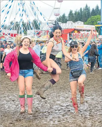  ??  ?? GIVING IT WELLY: Revellers Chelsea Higginbott­om, Pamela Butller and Kelly Brown enjoy the mud. Picture: Julie Howden