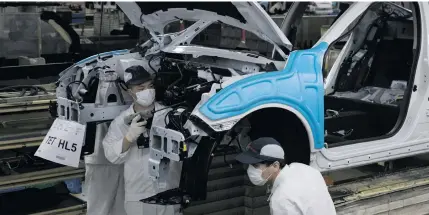  ?? AP PHOTO ?? In this April 8, 2020 photo, employees work on a car assembly line at the Dongfeng Honda Automobile Co., Ltd factory in Wuhan in central China’s Hubei province.