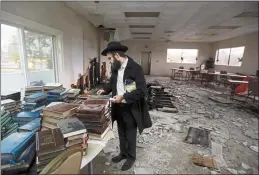  ?? NHAT V. MEYER — BAY AREA NEWS GROUP ?? Rabbi Mendel Weinfeld examines damaged books on Dec. 22after a fire at the Chabad House in San Jose.