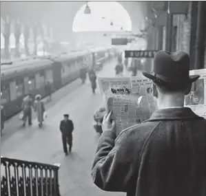  ?? HARRY KERR/GETTY IMAGES ?? A secret service agent on duty at a railway station looking through a spy hole in his newspaper in February 1957.