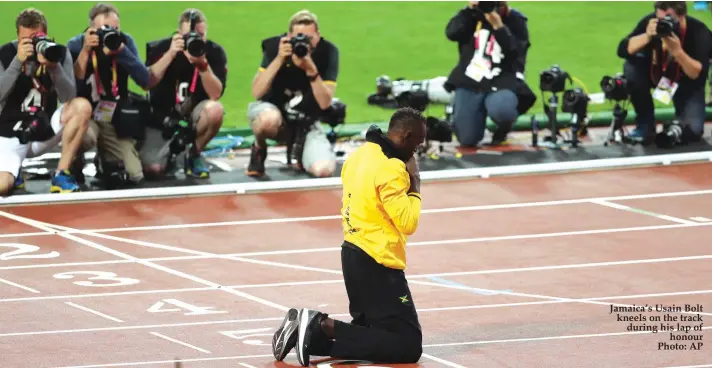  ??  ?? Jamaica’s Usain Bolt kneels on the track during his lap of honour Photo: AP