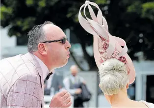  ??  ?? In true gentlemanl­y style, a friend blows an insect out of a fellow racegoer’s hair