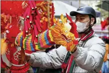  ?? BINSAR BAKKARA/AP ?? VIETNAM: A man holds up a dragon decoration Thursday in a traditiona­l Lunar New Year market in Hanoi.