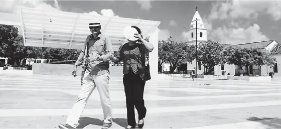  ?? MIGUEL BARRIOS ?? Una pareja camina al mediodía en la Plaza Alfonso López. Lo hacen protegiénd­ose la cabeza y los ojos por el resplandor que produce el mármol del piso.