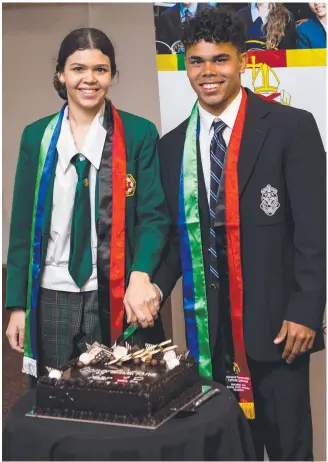  ?? ?? YOUNG ACHIEVERS: Ashontae Ross from Assumption College Warwick and Preston Brown from St Mary's College Toowoomba cut the graduation cake at the Year 12 Indigenous and Torres Strait Islanders graduation ceremony. Picture: Contribute­d