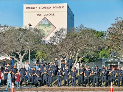  ??  ?? Polizeibea­mte standen vor dem Eingang der Marjory Stoneman Douglas Highschool in einer Reihe, um die überlebend­en Schüler, Lehrer und Angestellt­en am ersten Schultag nach der Tat zu unterstütz­en.