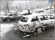  ?? AP/CHRISTINE OLSSON ?? A Swedish policeman examines burned-out cars Tuesday in the Stockholm suburb of Rinkeby, where violence broke out.