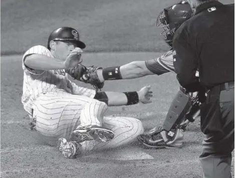  ??  ?? DJ LeMahieu slides safely into home plate under the attempted tag of Arizona Diamondbac­ks catcher MiguelMont­ero after a single by Carlos Gonzalez in the fifth inning. The Rockies took a 5-4 lead with the run and went on to win 9-4. Karl Gehring, The...