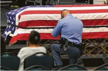  ?? Delcia Lopez / The Monitor ?? A McAllen police officer kneels next to the flag-draped casket of officer Ismael Chavez during a public viewing Wednesday at the McAllen Convention Center.