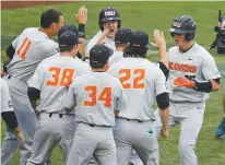  ??  ?? Oregon State’s Adley Rutschman, right, is congratula­ted near the dugout after his solo home run against North Carolina during Wednesday’s College World Series eliminatio­n game in Omaha, Neb.