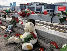  ?? EVGENIA NOVOZHENIN­A/REUTERS ?? Flowers and toys are placed on the road in front of the burnt-out Crocus City Hall following the deadly attack last Friday