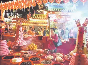  ??  ?? A woman prays to Ti Kong as she is surrounded by food offerings.