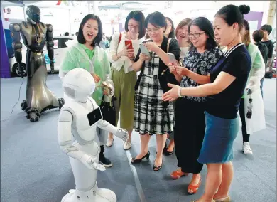  ?? WU KAI / FOR CHINA DAILY ?? A group of women interact with a robot at the National Mass Innovation Entreprene­urship Week, which opened on Friday in Shanghai.