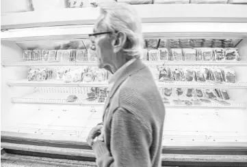  ?? — WP-Bloomberg photo ?? A customer walks past a depleted meat case in a Caracas grocery store last month. The economic crisis at the root of food and other scarcities is causing new panic among Venezuelan­s, who increasing­ly blame President Nicolas Maduro for their hardships.