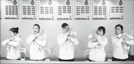  ?? ?? Students at Ayi University, a training program for domestic helpers, practice on baby dolls during a course teaching childcare in Beijing, China December 5, 2018. (REUTERS/Thomas Peter/file photo