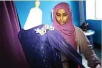  ??  ?? Hawa Adan Hassan checks her new finished fashion design.