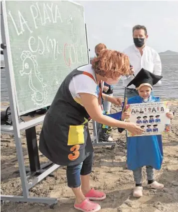  ??  ?? Cecilia, maestra de Infantil, entrega la orla a uno de sus alumnos