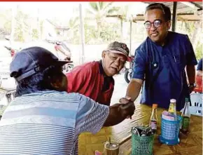  ?? PIC BY MOHD AZREN JAMALUDIN ?? Barisan Jemaah Islamiah Se-Malaysia candidate Datuk Dr Badhrulhis­ham Abdul Aziz (right) greeting a patron at a food stall during campaign rounds in Pontian yesterday.