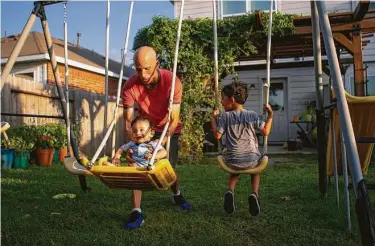  ?? Photos by Mark Mulligan / Staff photograph­er ?? Ron Burke helps his youngest son, Evan, swing, while Ezra enjoys swinging on his own.