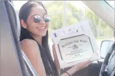  ?? LYNN KUTTER ENTERPRISE-LEADER ?? Farmington High senior, Grecia Suchil, picks up her cap and gown for graduation last week from Balfour. She is displaying a diploma plaque, one of many graduation items that can be ordered from Balfour. Seniors picked up their graduation items by drive through at the front of the high school.