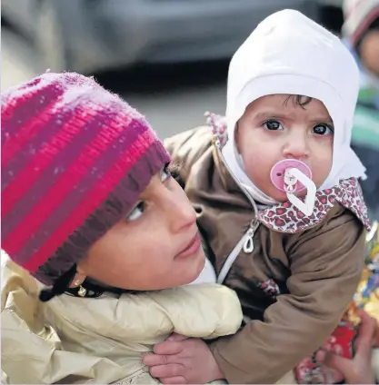  ??  ?? Syrian children wait for other members of their family after they crossed into Turkey at the Cilvegozu border gate with Syria, near Hatay. It was not immediatel­y clear where in Syria most people that crossed into Turkey were coming from, but one woman...