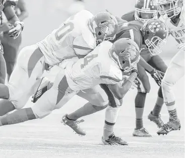  ?? Leslie Plaza Johnson ?? Yates defensive lineman Steven Wright (50) and defensive back Kertius Oreaboe (4) tackle Wheatley running back Darius Garner during the District 11-4A game at Barnett Stadium on Saturday night.