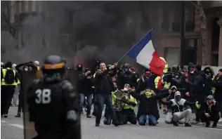  ?? (Benoit Tessier/Reuters) ?? A PROTESTER WAVES a French flag during clashes with Paris police yesterday at a demonstrat­ion by the ‘yellow vests’ movement.
