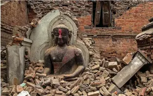  ??  ?? Debris: A Buddha statue survived after a temple collapsed in the city