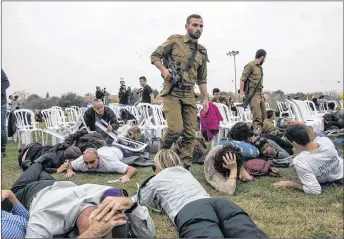  ??  ?? Israeli take cover during rocket attack siren warning in kibbutz Kfar Aza near the Israel and Gaza border, Israel, Friday. Israelis gathered to mark a birthday of Oron Shaul who was killed during the last war in Gaza and Hamas is believed to hold his...