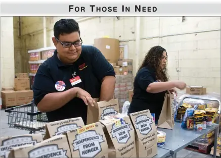  ??  ?? RECORDER PHOTO BY CHIEKO HARA Christian Cornejo, left, and Amber Gutierrez pack food items into bags Thursday at Grocery Outlet in Portervill­e.