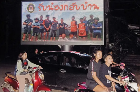  ?? Pictures: AFP ?? SAFE AT LAST. Motorists pass by a billboard displaying a photograph of the Thai children’s football team Wild Boars and their coach with a message reading ‘welcome home brothers’ in Chiang Rai yesterday, following their rescue.