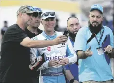  ?? JOHN RAOUX/AP ?? FANS TAKES SELFIE PHOTOS WITH KEVIN HARVICK (CENTER) in the garage area during a practice session for the Daytona 500 auto race at Daytona Internatio­nal Speedway on Feb. 17 in Daytona Beach, Fla.