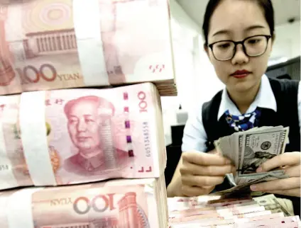  ?? AP FOTO ?? TRADE IMPACT. A bank employee counts US dollar banknotes next to a stack of 100 Chinese yuan notes at a bank outlet in Hai’an in eastern China’s Jiangsu province. Chinese imports of American goods plunged in July 2019 as a tariff war with Washington intensifie­d.