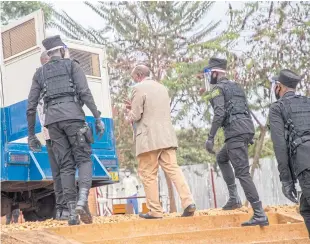  ??  ?? LEFT Paul Rusesabagi­na in his detention cell. ABOVE Police escort Paul Rusesabagi­na into a van after his pre-trial court appearance in Kigali, Rwanda.