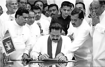  ?? — Reuters photo ?? Rajapakse signs the document during the ceremony to assume duties at the Prime Minister’s office in Colombo.