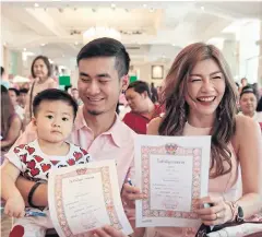  ?? PATIPAT JANTHONG ?? A couple, accompanie­d by their one-year-old son, shows their marriage certificat­es after the documents were issued by a registrar during an event, Season of Love @Bangkok, to celebrate Valentine’s Day at the Grand Postal Office in Bangkok’s Bang Rak...