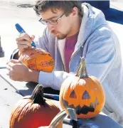  ?? JOHN SMIERCIAK/POST-TRIBUNE ?? Matthew Gagliardi a sophomore, draws a message on a pumpkin during a pumpkin toss from the parking garage at Purdue Northwest.