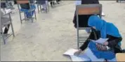  ?? AP ?? Jahantab Ahmadi writes the exam with her daughter on her lap.
