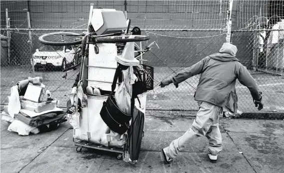  ?? Paul Chinn / The Chronicle ?? MARKAEL RAYVON: A homeless man living at the encampment at 14th and Mission streets hauls his belongings away from the camp after it was taken down so that a Public Works crew could clean up the debris and power-wash and disinfect the sidewalk. Complaints about camps on the 311 line increased fivefold in 2016 over the previous year.