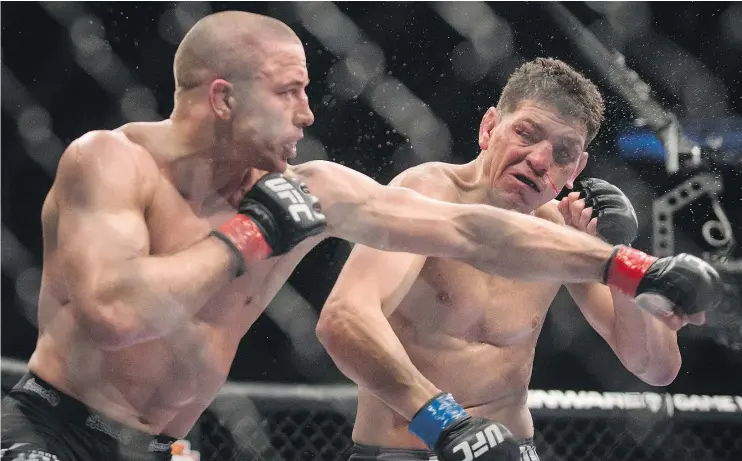  ?? — DARIO AYALA/POSTMEDIA NEWS FILES ?? Georges St-Pierre lands a punch on Nick Diaz in 2013. The Montrealer revealed Monday that he was no longer under contract with the UFC.